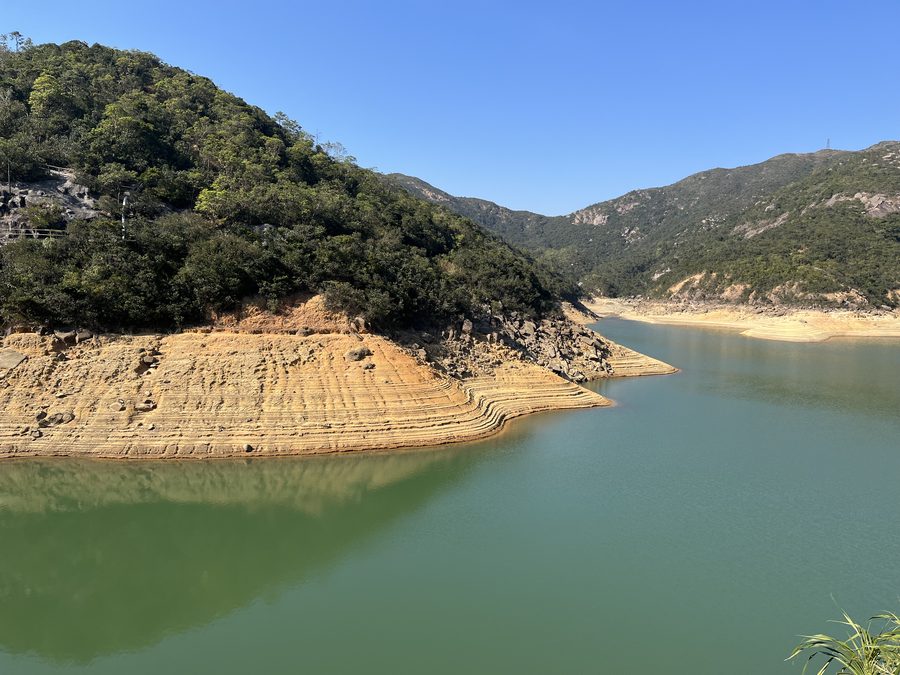 A reservoir drawn down between wooded hills